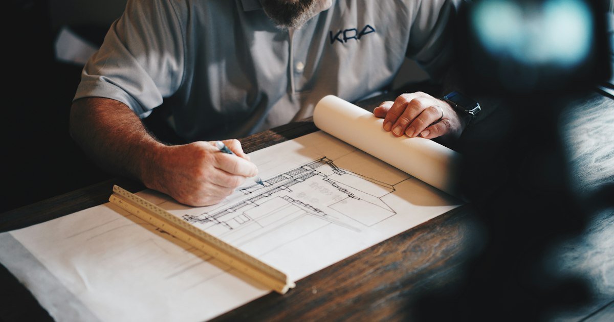 Arquiteto analisando a planta de uma construção sobre a mesa de trabalho